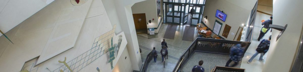The lobby of a building, with students walking on staircases and ramps.